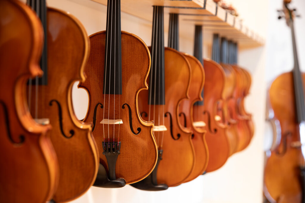 Viele Geigen hängen an der Wand.